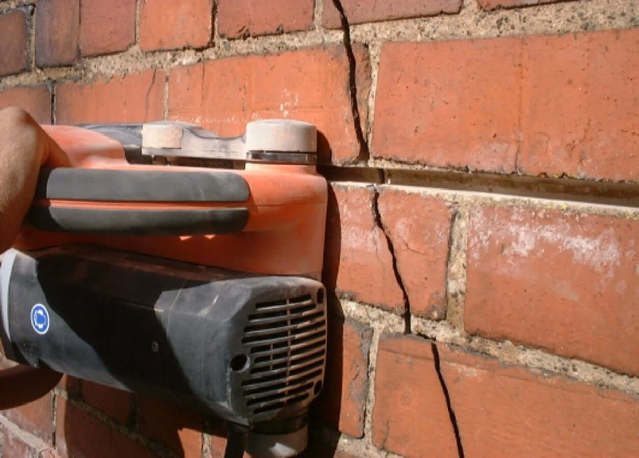 A wall chaser raking out a mortar joint for crack stitch repairs